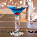 blue arrow cocktail in glass with a cherry