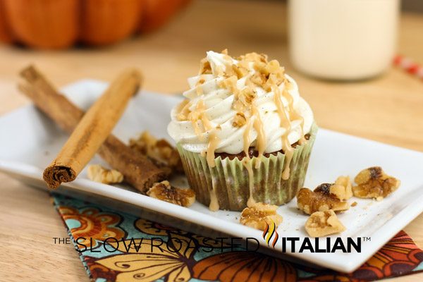 caramel apple cupcakes with cream cheese frosting swirled on top, sitting on white plate