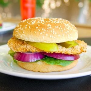 baked breaded chicken breast on bun with pickles and red onion