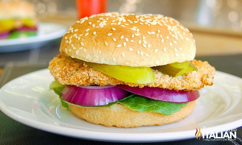 crispy chicken sandwich on sesame seed bun sitting on white plate