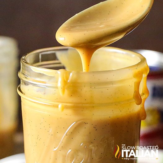 crockpot caramel dripping from spoon into glass jar