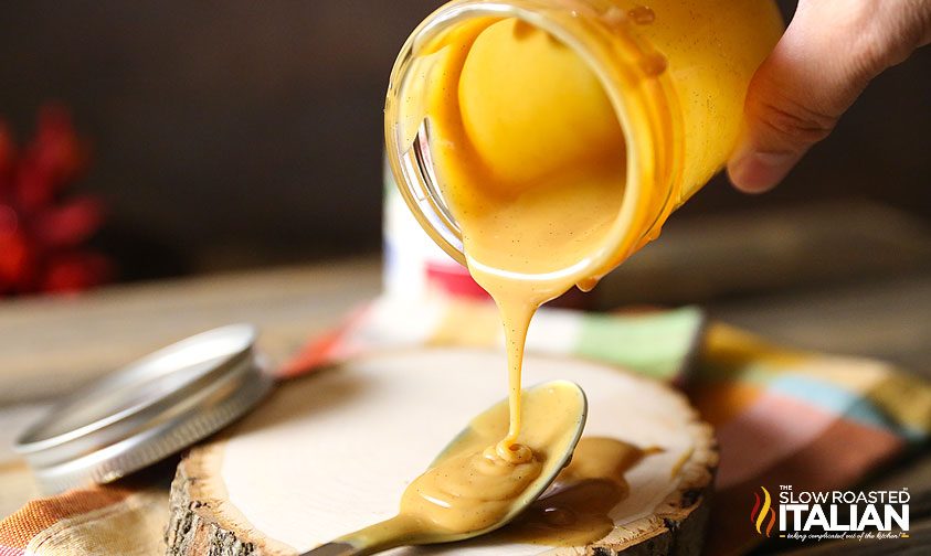 slow cooker dulce de leche dripping from jar onto spoon