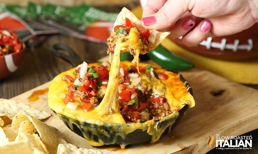 dipping tortilla chip into cheesy mexican dip