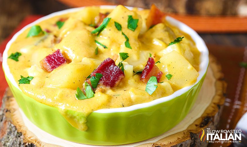 close up image of cheesy soup garnished with scallions and bacon