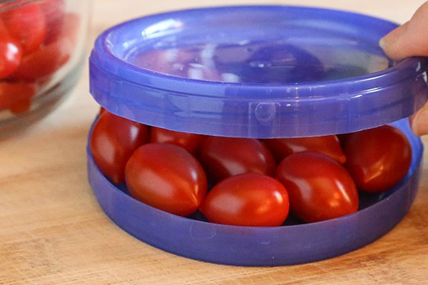 slicing a lot of cherry tomatoes between two plates