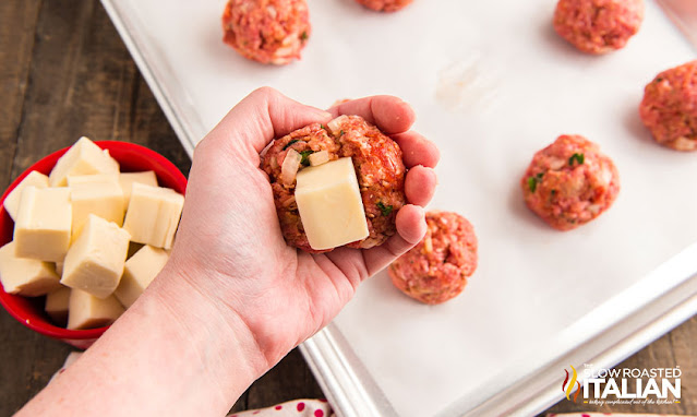 cube of white cheese inside meatball mixture