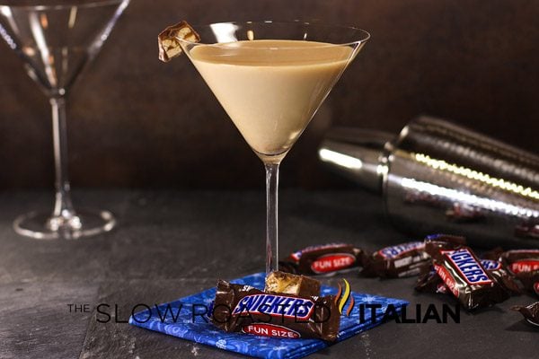 snickers martini in a glass surrounded by mini candy bars