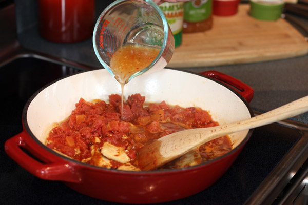 adding chicken stock to pan with tomatoes