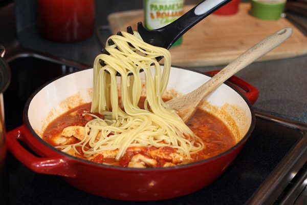 adding spaghetti to chicken parmesan pasta toss
