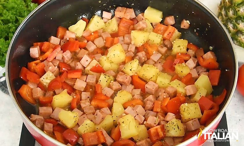 pineapple, ham and tomatoes cooking in a skillet