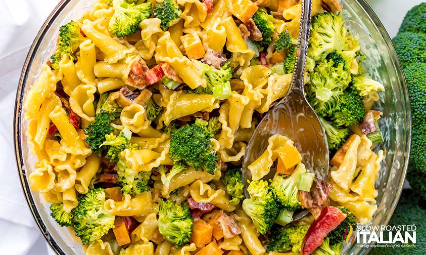 cheddar broccoli pasta salad in glass bowl with serving spoon