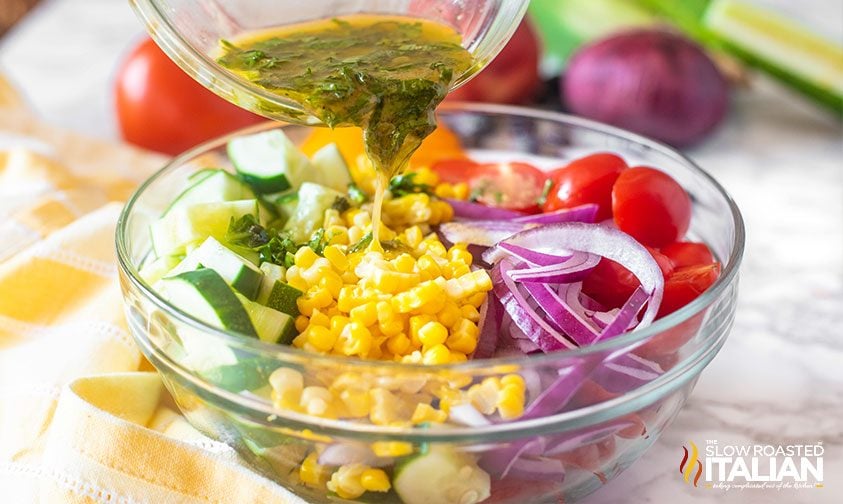 cucumbers, corn, tomatoes and red onion in glass bowl