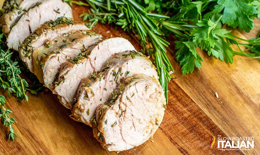 herb roasted pork tenderloin sliced on a board