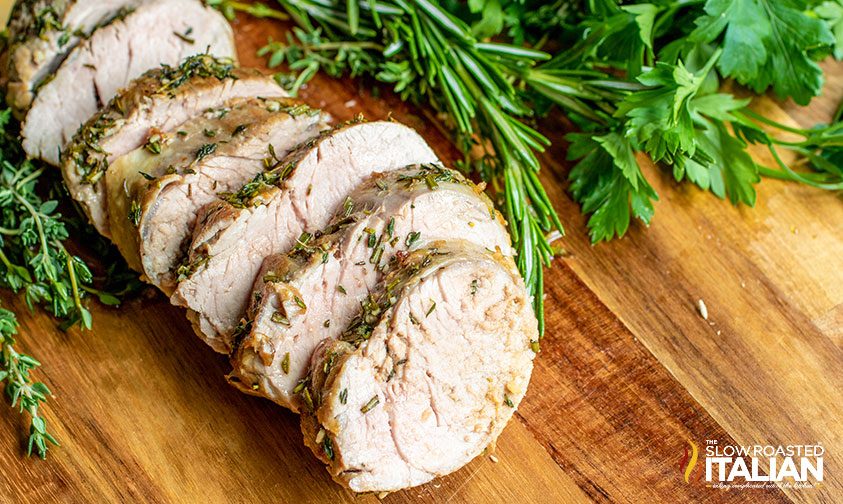 herb roasted pork tenderloin sliced on a board