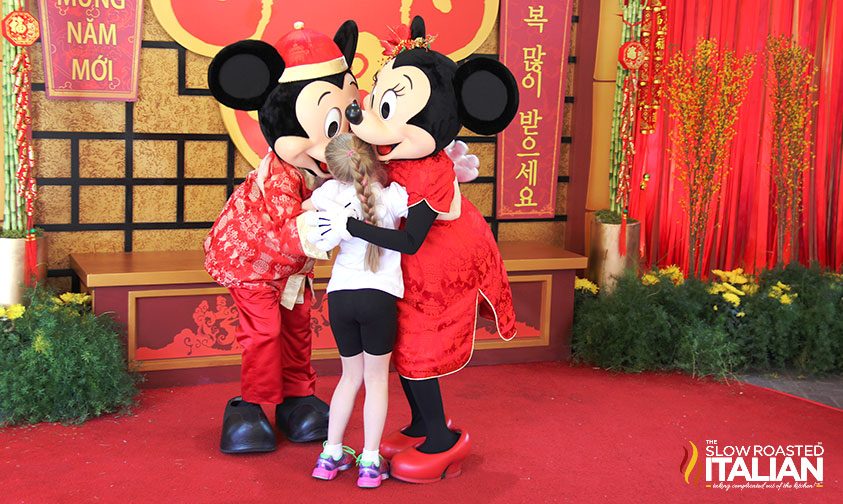 Mickey and Minnie hugging a little girl