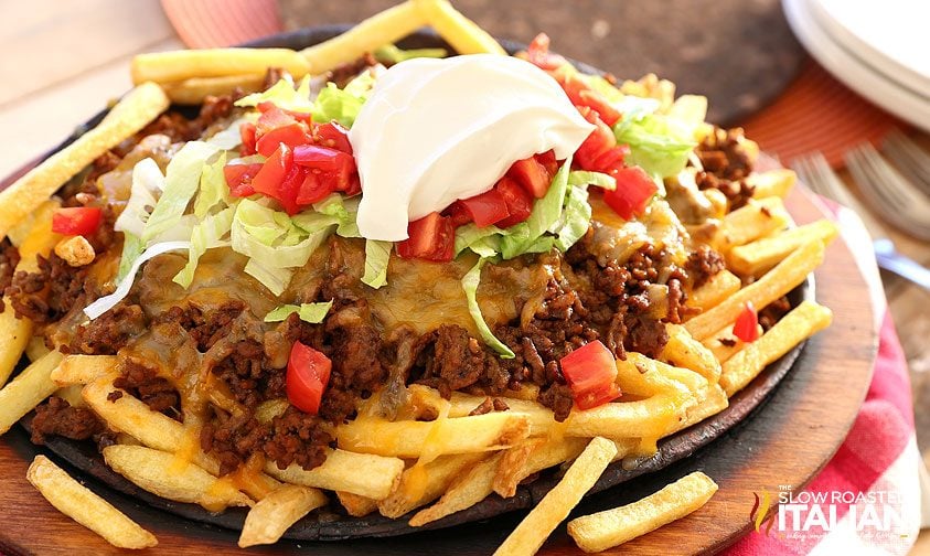 fully loaded cheesy taco fries on plate with sour cream