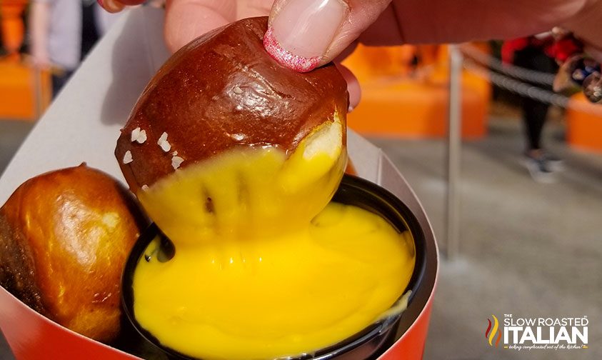 dipping soft pretzel bite into nacho cheese