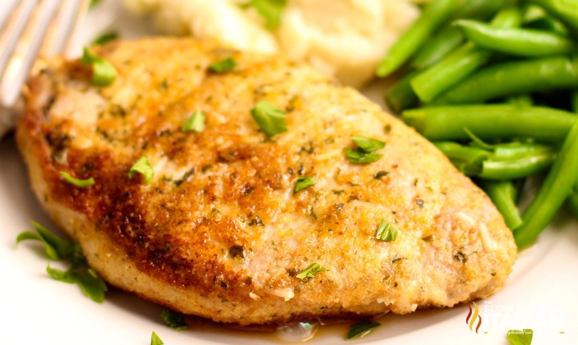 baked parmesan pork chop on plate with green beans