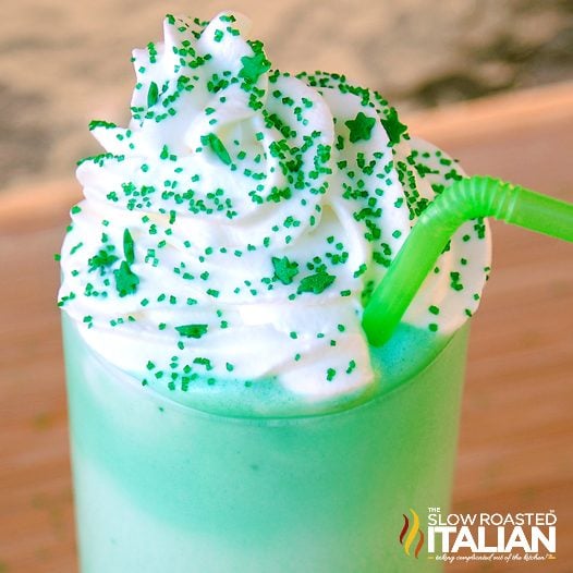 green milkshake in glass with whipped cream and sprinkles