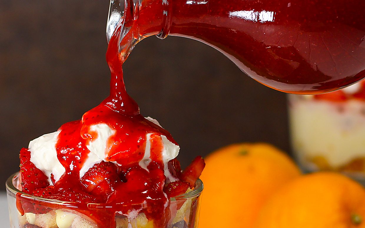 pouring simple dessert sauce with strawberries over ice cream