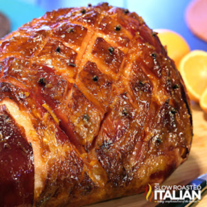 orange honey glazed ham on cutting board