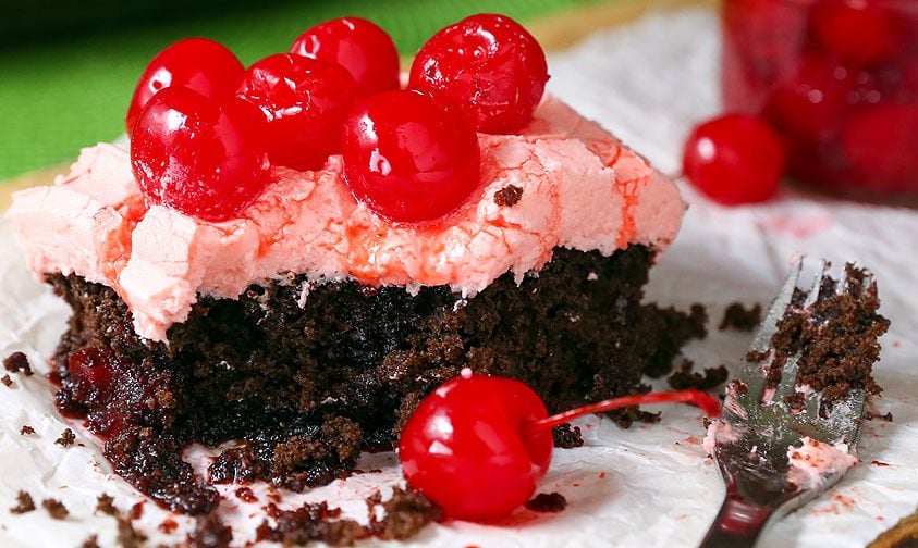 slice of chocolate cake with cherry frosting and maraschino cherries