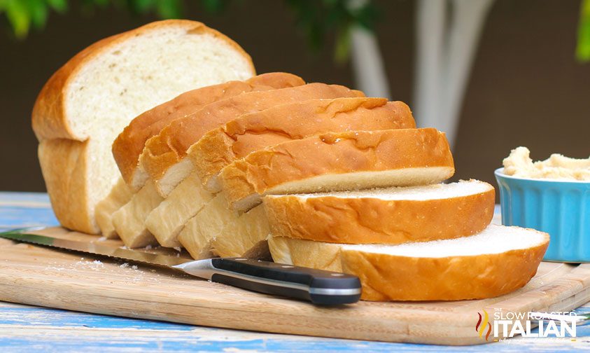 slices of Amish bread on wooden cutting board with serrated knife