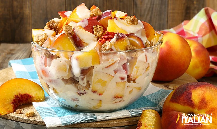 peach cobbler cheesecake salad in bowl with fresh peaches