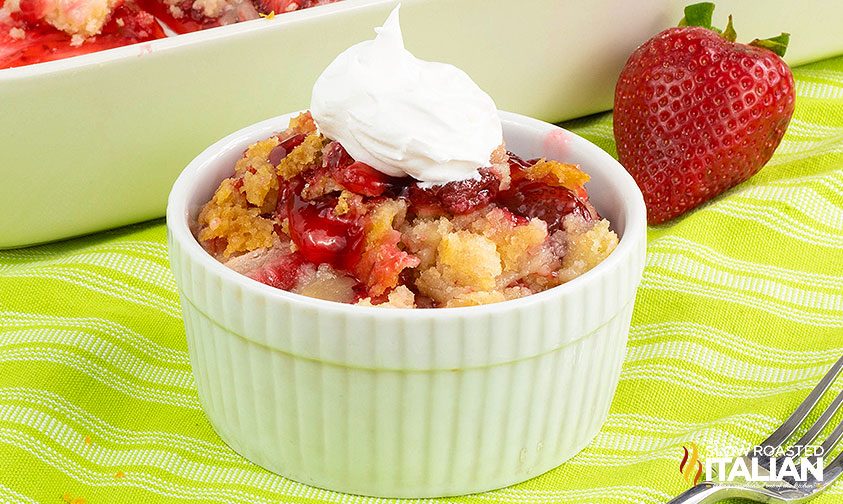 strawberry dump cake in bowl with dollop of whipped cream