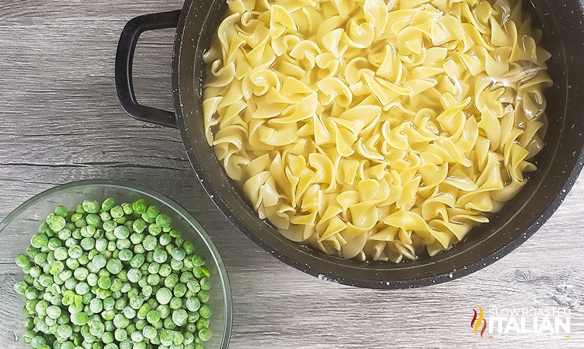 overhead: bowls with cooked egg noodles and frozen peas