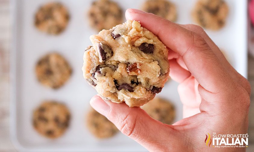 hand holding large piece of raw cookie dough