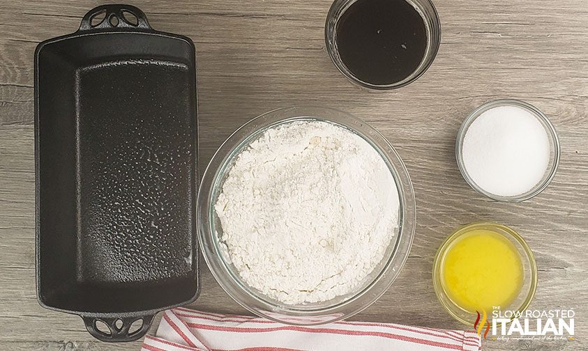 overhead: greased loaf pan next to bowls of flour, sugar, and whisked egg