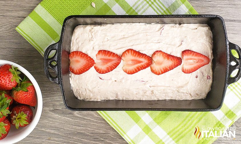 quick bread batter in loaf pan, topped with fresh berries