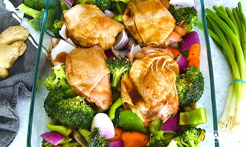 skin on chicken thighs and veggies with teriyaki sauce in baking pan