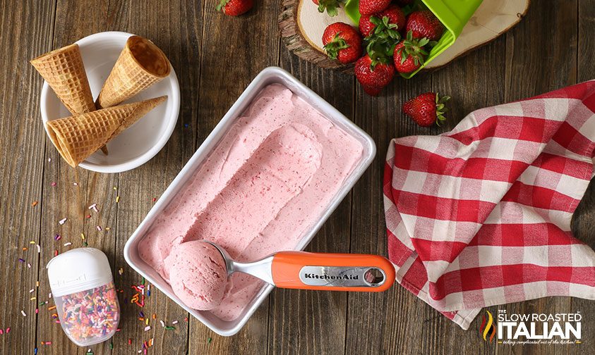 no churn strawberry ice cream on table with cones and ice cream scoop