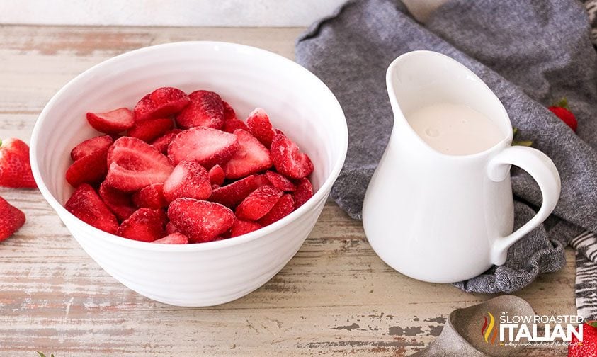 bowl of fresh berries next to pitcher of heavy cream