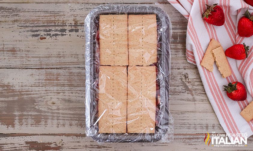 no bake strawberry dessert in loaf pan covered with plastic wrap