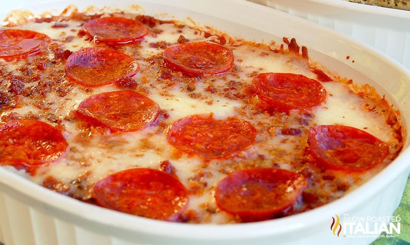 4 layer pizza dip with pepperoni and bacon in oval casserole dish