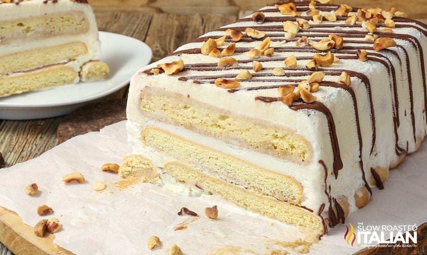 tiramisu cake with layers of ice cream and lady fingers topped with ganache and hazelnuts