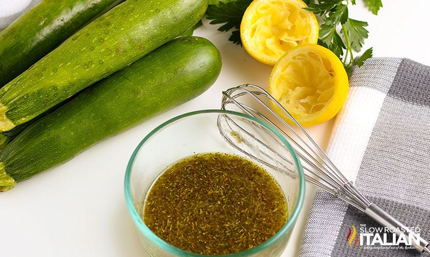 homemade Italian dressing on counter next to lemon and green summer squash