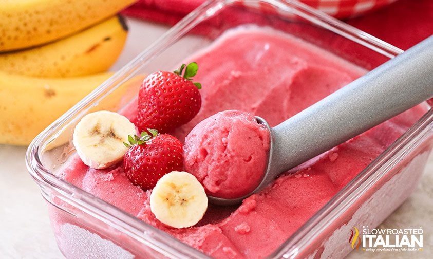 fresh strawberries and banana slices on top of strawberry banana ice cream