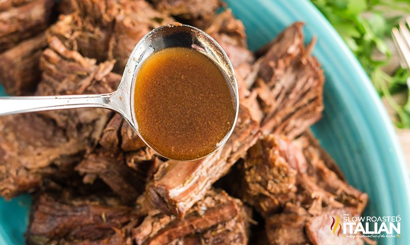 ladle of beef au jus over chuck roast