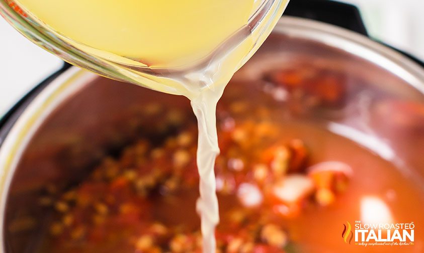 Instant Pot Lentil Soup pouring in chicken stock