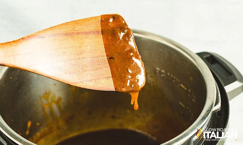 instant pot pork chop gravy coating a wooden spatula
