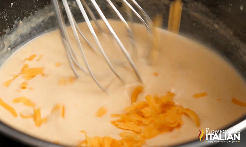 whisking shredded cheese into cream sauce