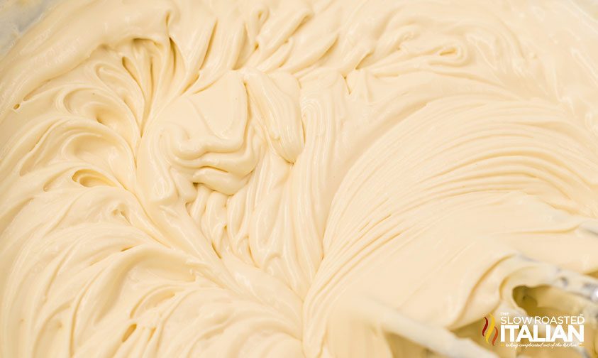 blending cream cheese with sugar in a large bowl.