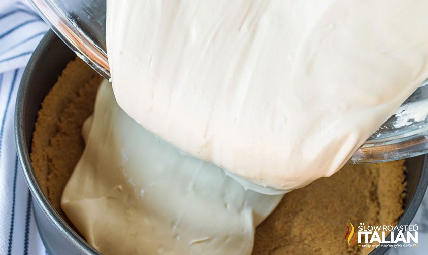 pouring cheesecake filling into the crust