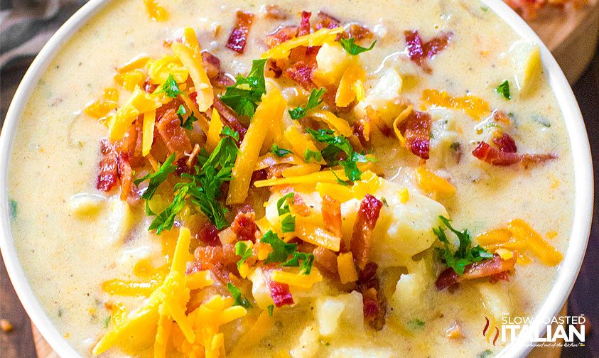bowl of crockpot potato soup with garnish of cheese, bacon, and scallions