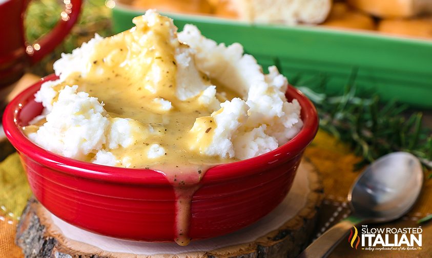 mashed potatoes in red bowl with gravy poured over it