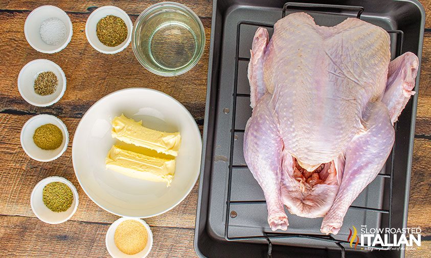 turkey in a square pan laying next to ingredients in glass bowls